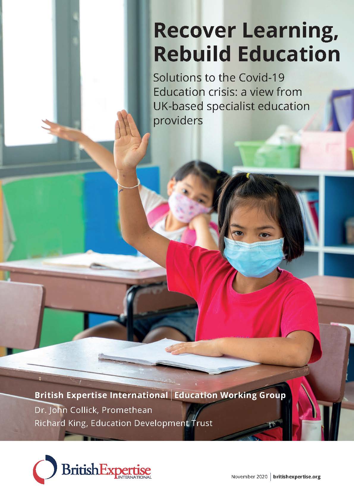 Two children raising hands in classroom, wearing facemasks