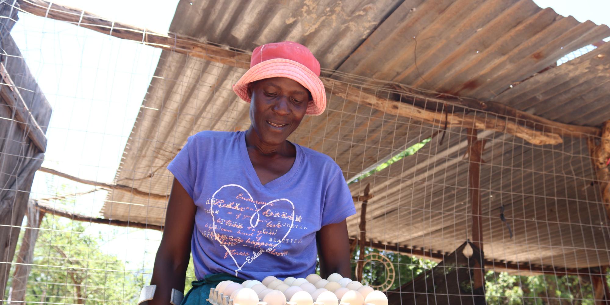 Woman carrying large crate of chicken eggs. 